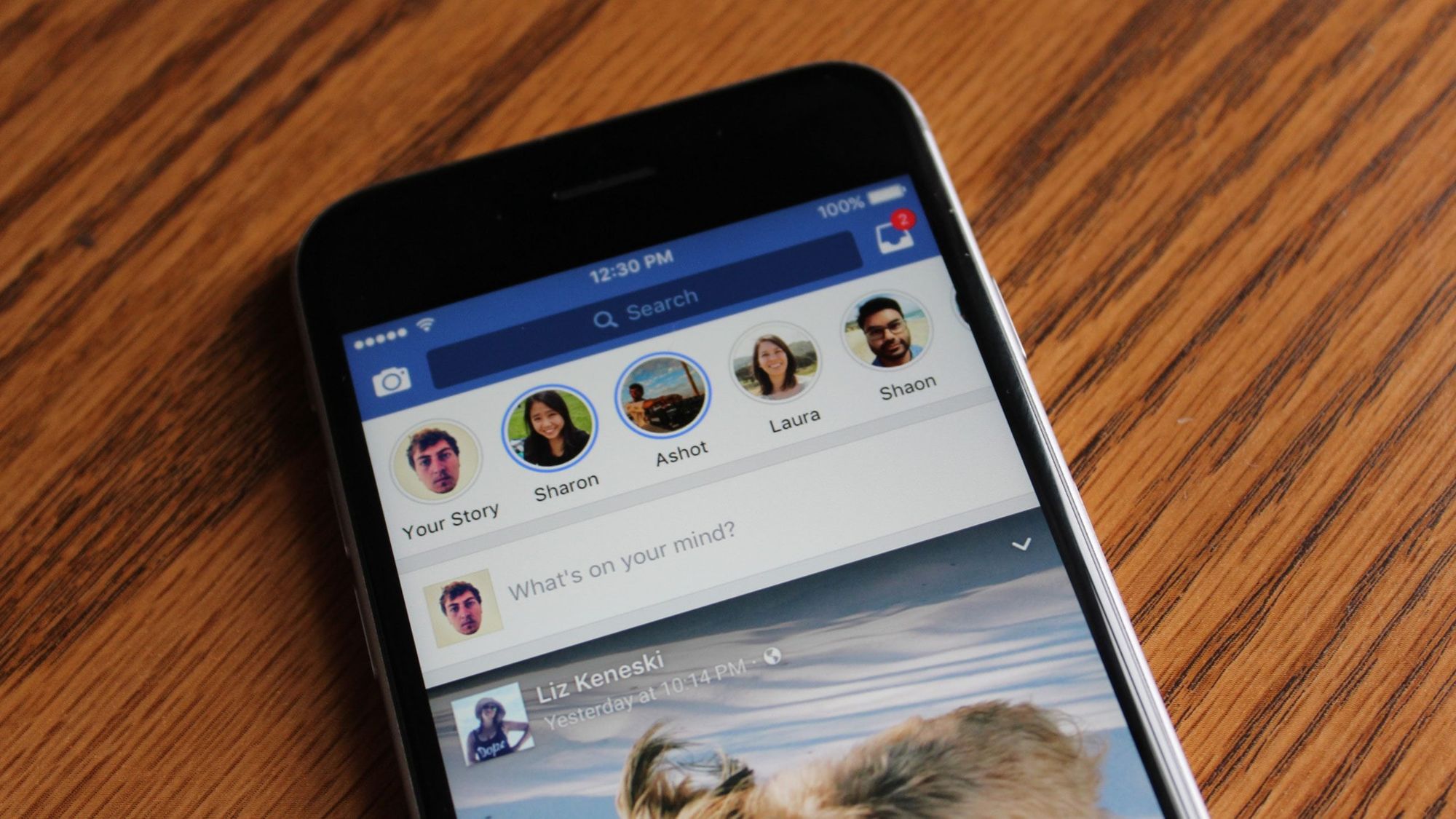 Gros plan d'une main tenant un smartphone à la verticale montrant une story Facebook en cours de lecture sur un écran complètement flouté